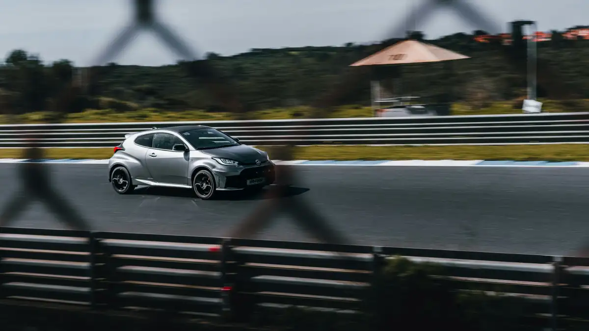 A silver car races on a racetrack.